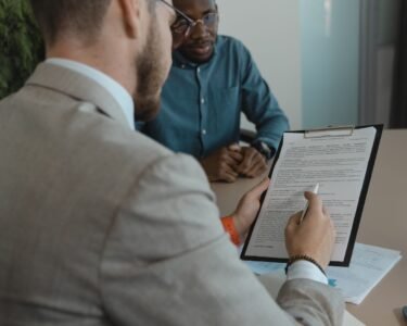 A recruiter reviews a candidate's documents during a job interview in a modern office setting.